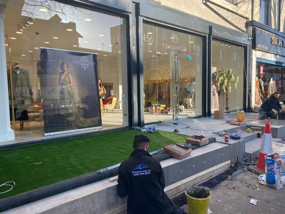Operatives finishing the shopfront threshold and paving